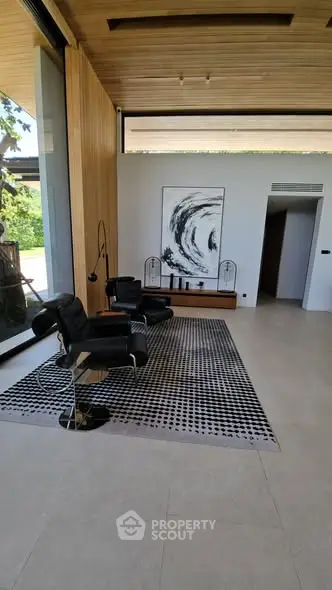 Modern living room with stylish black chairs and abstract art, featuring floor-to-ceiling windows and wooden accents.