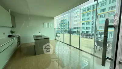 Modern kitchen with open layout and large glass doors leading to a spacious balcony with city views.