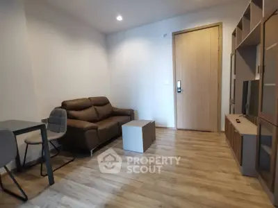 Modern living room with wooden flooring, brown leather sofa, and sleek storage unit.