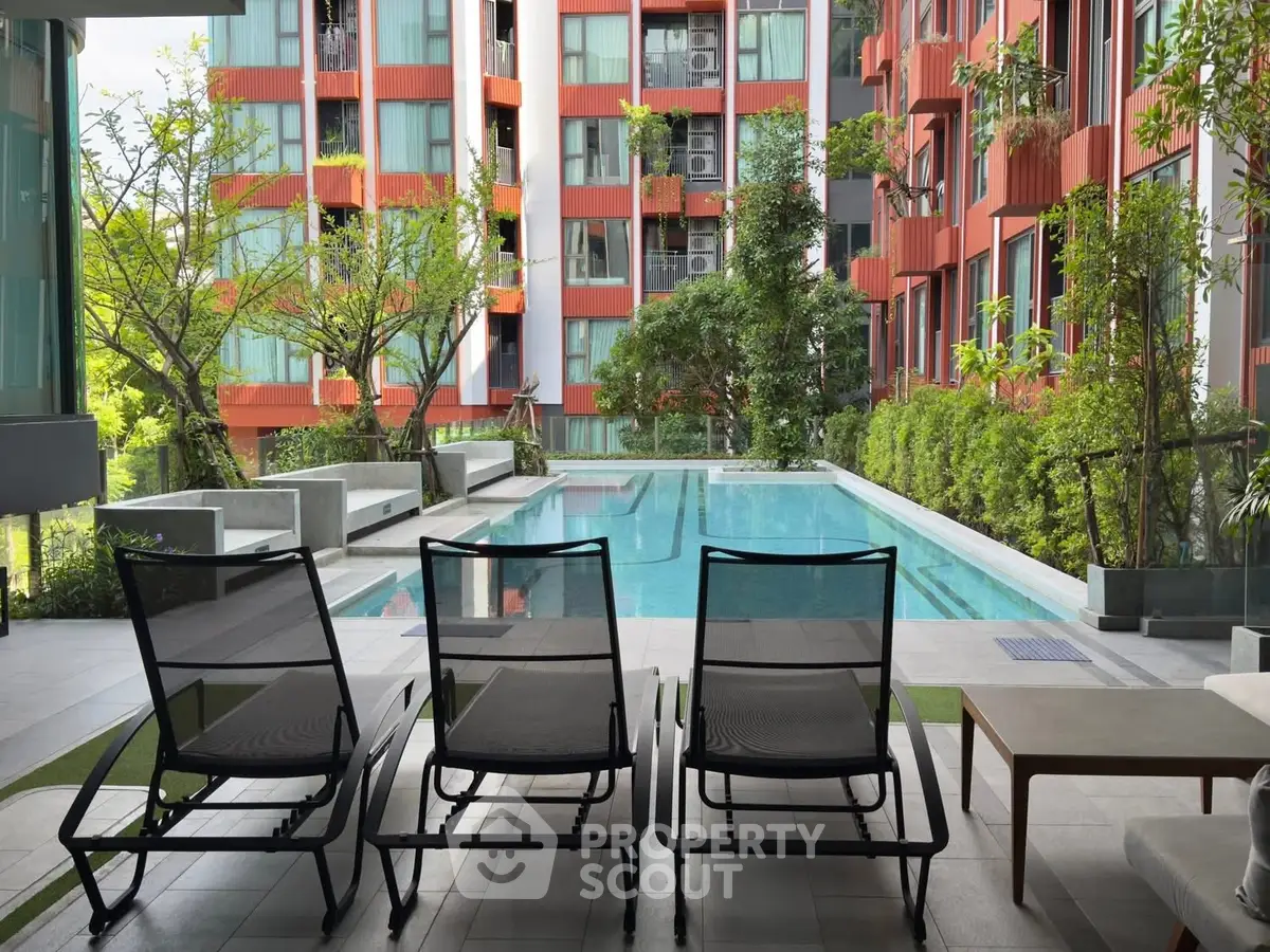 Luxurious apartment complex with a stunning poolside view and modern outdoor seating area.
