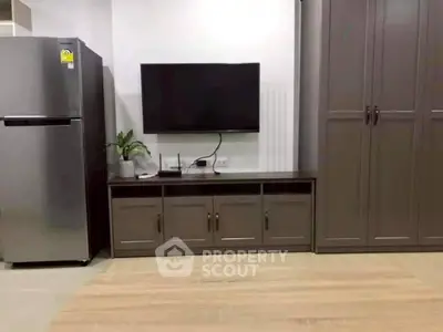 Modern living room with sleek TV setup and stainless steel fridge