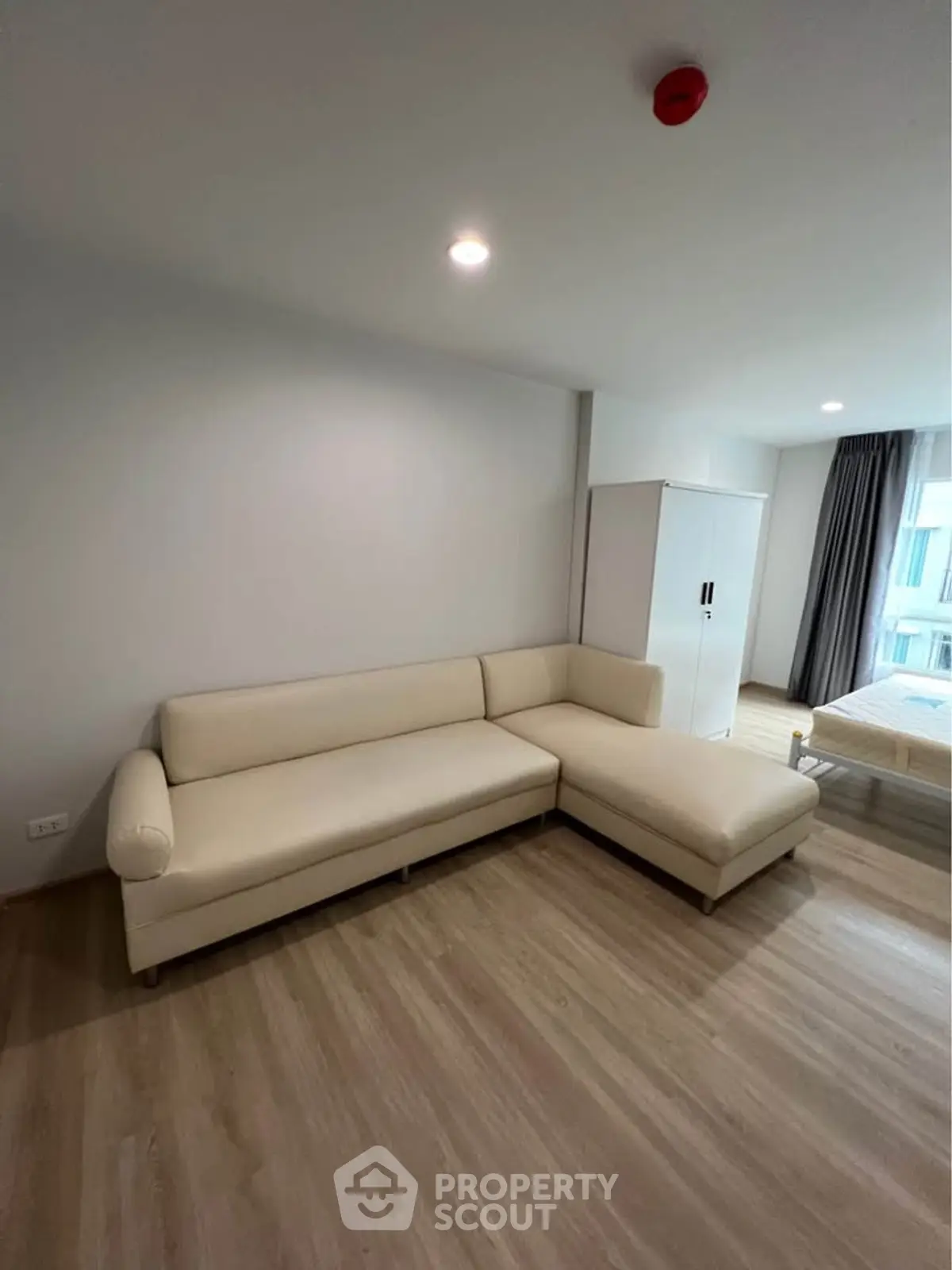 Spacious living room with modern beige sectional sofa and wooden flooring