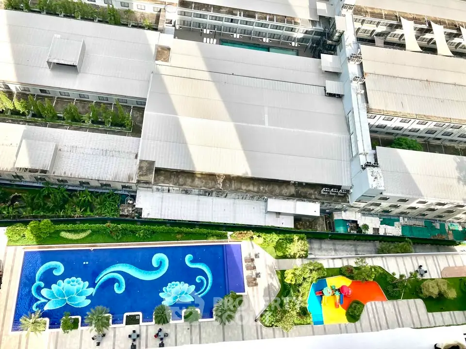 Stunning aerial view of modern apartment complex with vibrant pool and lush greenery.