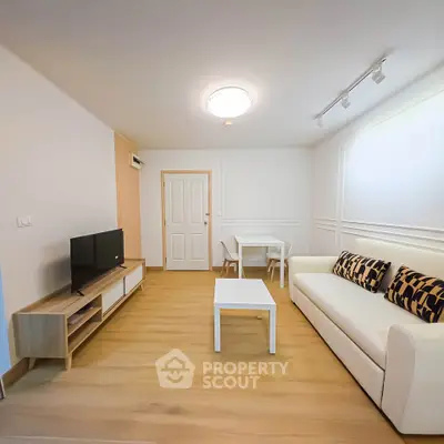 Modern living room with stylish furniture and wooden flooring, featuring a cozy sofa and sleek TV unit.