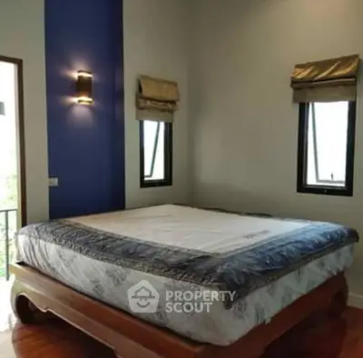 Cozy bedroom with elegant wooden bed and natural light from windows.