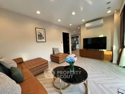 Spacious modern living room with elegant decor and large TV, perfect for relaxation and entertainment.