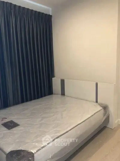 Modern bedroom with new mattress and dark curtains in a minimalist design.