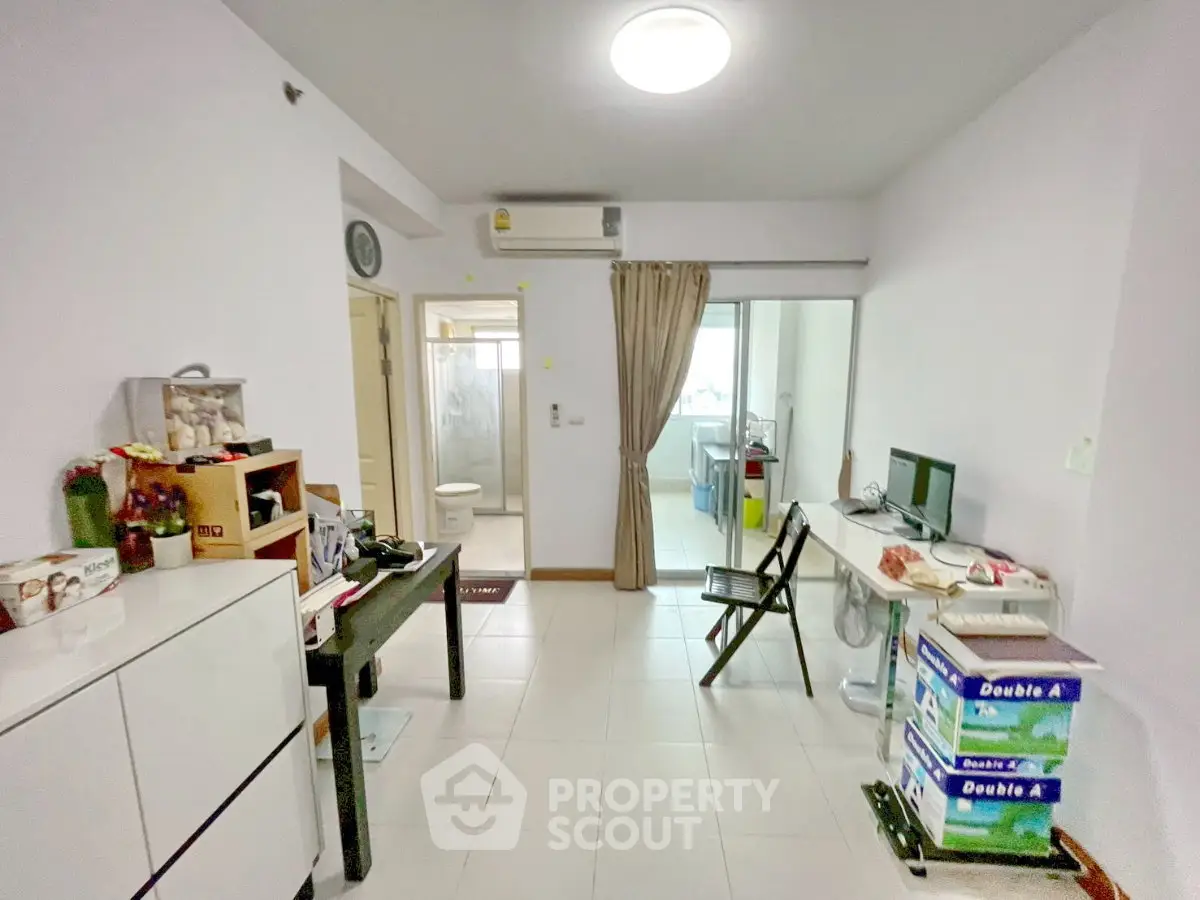 Cozy living room with modern decor and natural light, featuring a compact workspace and stylish furnishings.