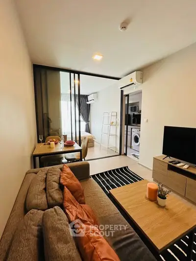 Modern living room with cozy seating and open view to adjacent room, featuring stylish decor and natural light.