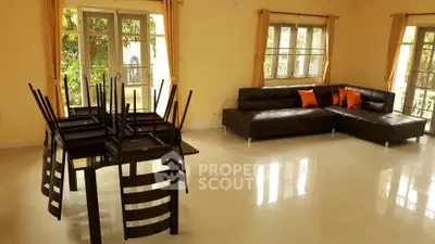 Spacious living room with modern black leather sofa and dining area