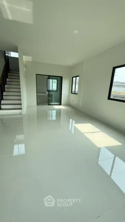Spacious modern living room with glossy tiled floor and staircase