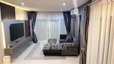 Modern living room with sleek furniture and large TV, featuring elegant curtains and ambient lighting.