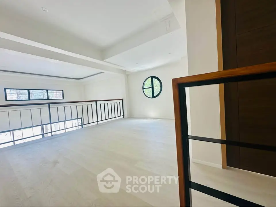Spacious modern loft with large windows and elegant railing, perfect for stylish urban living.