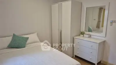 Cozy bedroom with white furniture and a mirror, perfect for relaxation.