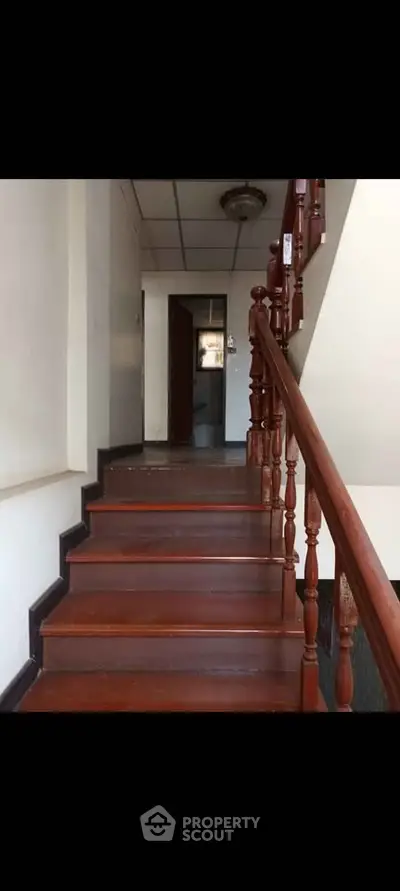 Charming interior staircase with wooden railing leading to upper floor in cozy home.