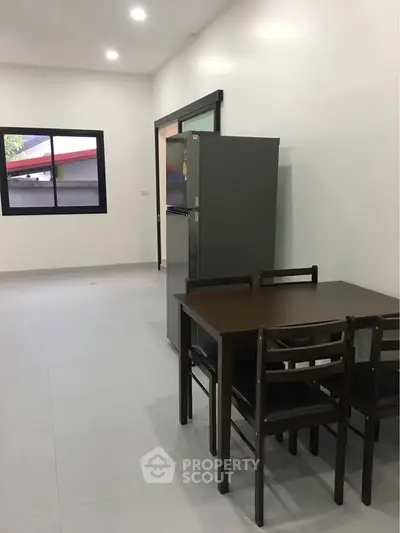 Modern dining area with sleek table and chairs, adjacent to a compact kitchen space.