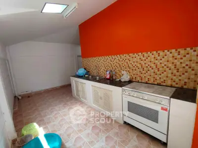 Spacious kitchen with vibrant orange accent wall and modern appliances