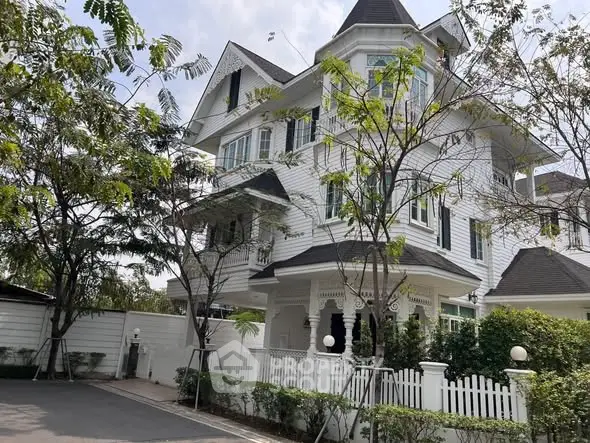 Charming Victorian-style house with white picket fence and lush greenery, perfect for family living.