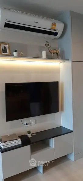 Modern living room with sleek TV setup and air conditioning unit.