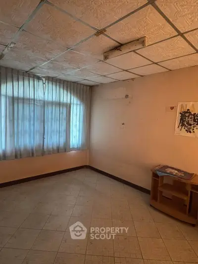 Spacious room with large window and tiled floor, ideal for customization.