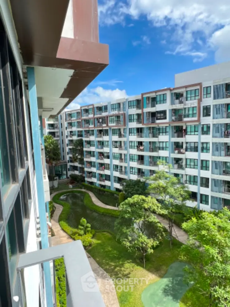 Modern apartment complex with lush green garden and clear blue sky view