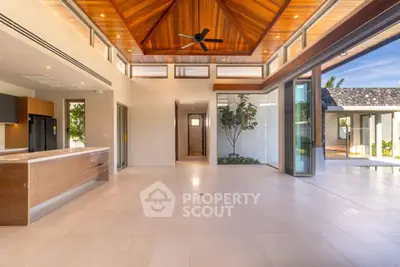 Stunning open-plan living area with high wooden ceilings and large glass doors.