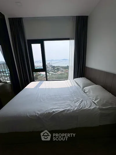 Stunning bedroom with panoramic sea view from large window, perfect for serene living.