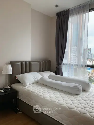 Cozy bedroom with city view, featuring a plush bed and elegant curtains.