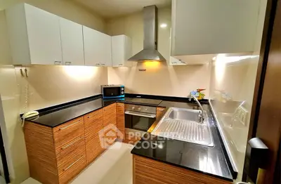 Modern kitchen with sleek cabinets, built-in oven, and stainless steel sink in a compact layout.