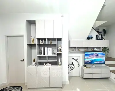 Modern living room with stylish shelving and TV unit, featuring elegant decor and neutral tones.