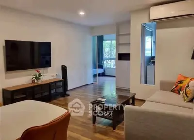 Modern living room with hardwood floors, wall-mounted TV, and cozy seating area.