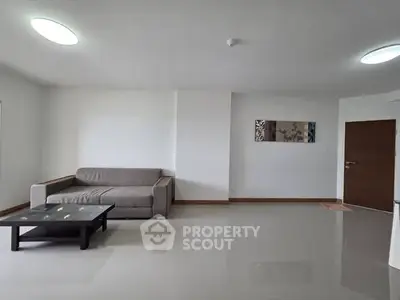 Spacious modern living room with sleek sofa and coffee table, perfect for relaxation.