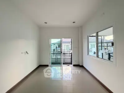 Spacious empty room with large window and balcony view in modern apartment.