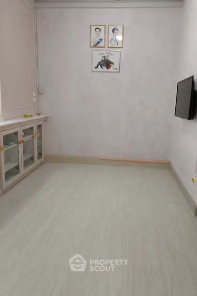 Spacious room with light wood flooring and wall-mounted TV, ideal for modern living.