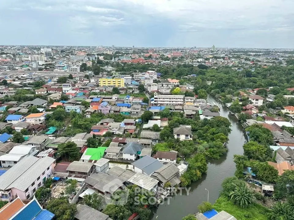 Aerial view of a vibrant urban neighborhood with diverse rooftops and lush greenery along a winding river.