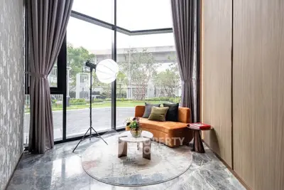 Luxurious corner unit with floor-to-ceiling windows and stylish decor, offering a serene garden view.