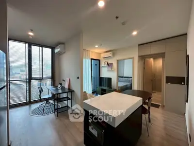 Modern open-plan living room with kitchen and study area, featuring sleek design and natural light.