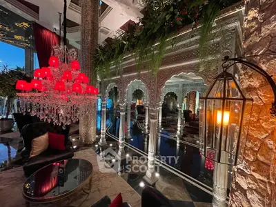 Luxurious living room with ornate decor and red chandelier, perfect for elegant gatherings.