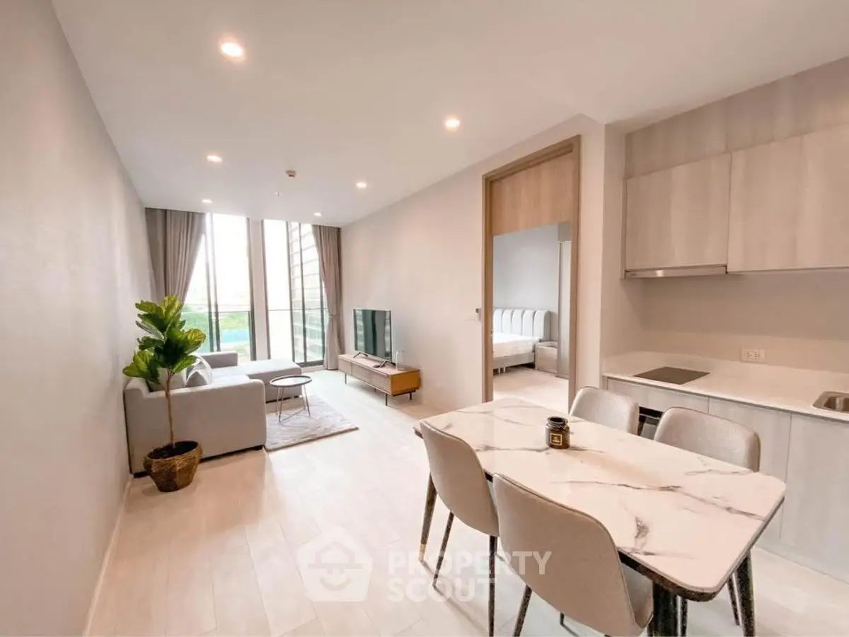Modern open-plan living room with dining area and kitchen in a bright apartment.