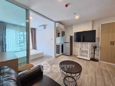 Modern living room with open layout, featuring sleek furniture and a view into a cozy bedroom.
