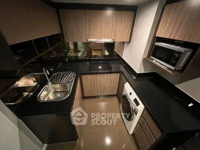 Modern kitchen with sleek black countertops, built-in appliances, and stylish wooden cabinetry.