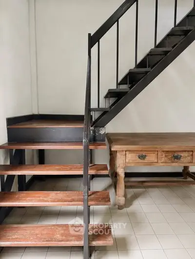 Stylish industrial staircase with wooden steps and rustic table in modern interior