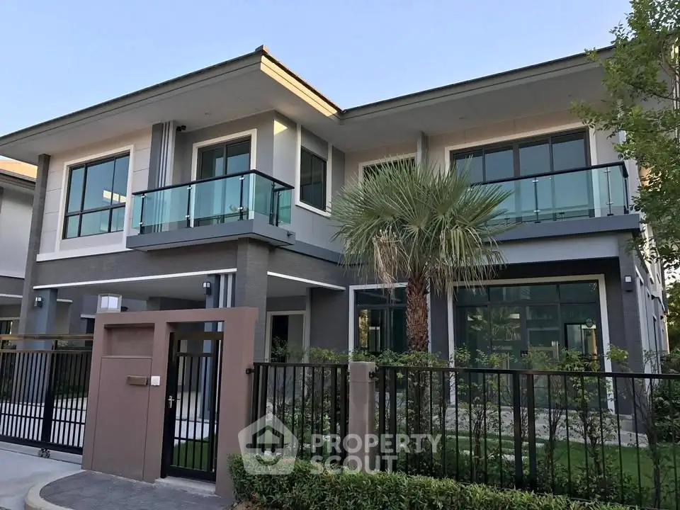 Modern two-story house with glass balconies and lush landscaping