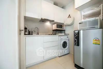Modern compact kitchen with washing machine and microwave in sleek white cabinetry.