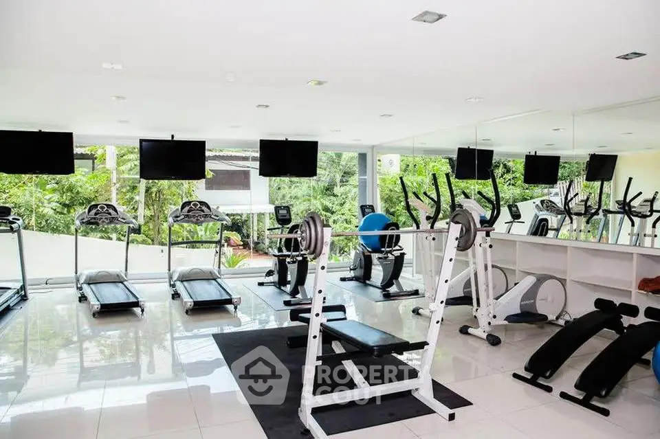 Modern gym with state-of-the-art equipment and lush garden view, perfect for fitness enthusiasts.