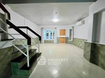 Spacious living room with modern staircase and large windows for natural light.
