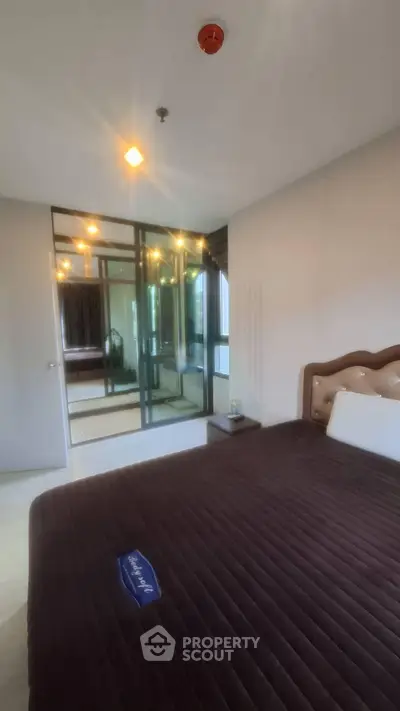 Spacious bedroom with modern glass wardrobe and cozy lighting in a stylish apartment.