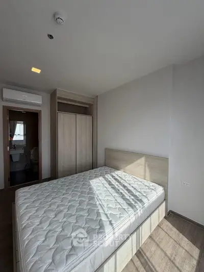 Modern bedroom with natural light and minimalist design, featuring a comfortable bed and sleek wardrobe.