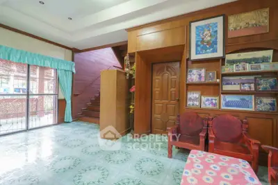 Charming living room with wooden accents and staircase, featuring large windows and decorative elements.