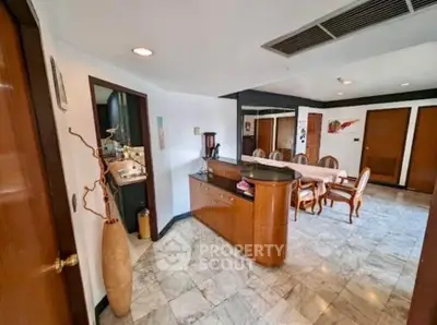 Spacious dining area with elegant wooden furniture and marble flooring in a modern home.